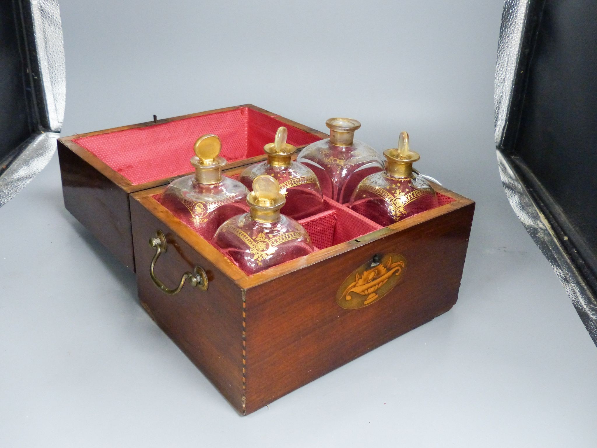 A mahogany inlaid decanter box containing five gilt decorated decanters